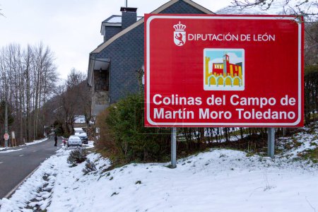 Ein rotes Schild mit dem langen Namen einer spanischen Stadt an einem verschneiten Tag