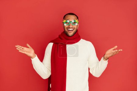Photo for Shrugging Man Smiling Studio. Confused Multiracial Guy Standing with No Idea Gesture, Shrugging Shoulders Raising Hands. New Year Concept. Indoor Studio Shot Isolated on Red Background - Royalty Free Image