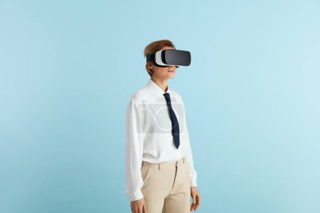 Téléchargez les photos : Femme d'affaires concentrée essayant VR. Portrait de fille à la découverte de nouvelles technologies portant un casque de réalité virtuelle, vision 3D futuriste. Studio intérieur isolé sur fond bleu - en image libre de droit