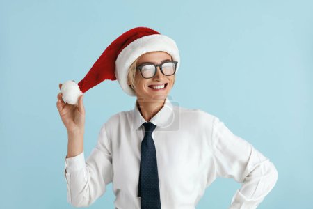Photo for Winner Businesswoman Rejoicing Studio. Extremely Happy Lady in Santa Hat Posing Camera, Feeling Energetic and Lively. Isolated on Blue Background - Royalty Free Image