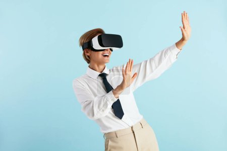 Téléchargez les photos : Happy Businesswoman Essayer VR. Portrait of Amazed Girl Découvrir les nouvelles technologies Porter un casque de réalité virtuelle, Vision 3D futuriste. Studio intérieur isolé sur fond bleu - en image libre de droit
