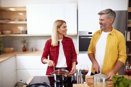 Téléchargez les photos : Couple cuisiner à la cuisine. Dîner de cuisine en famille des aînés ensemble à la maison. L'homme positif coupe des légumes biologiques frais pour la salade. Une alimentation saine sur le concept de week-end romantique - en image libre de droit