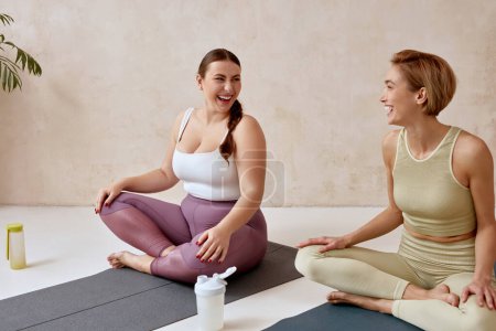 Photo for Smiling Woman Talking After Yoga. Female Friends Talking After Yoga Session Together At Home. Attractive Girls In Sportswear Sitting On Mat Spending Free Leisure Time - Royalty Free Image