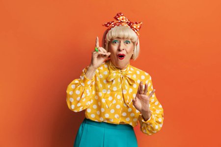 Photo for Senior Woman Having Idea. Happy Grandmother Pointing Finger Up With Successful Idea Over Orange Background. Exited And Happy - Royalty Free Image