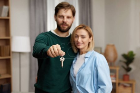 Foto de Happy Couple Holding Key. Happy Young Family Holding Key To New Home On Moving Day. Real Estate Owners Embrace Proud Buying Property - Imagen libre de derechos