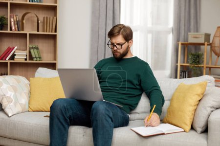 Foto de Serious Man Working Laptop. Bearded Guy Work At Notebook At Home During Weekend. Technology Man Concept - Imagen libre de derechos
