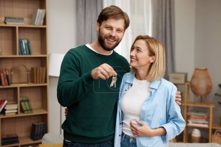 Foto de Happy Couple Holding Key. Happy Young Family Holding Key To New Home On Moving Day. Real Estate Owners Embrace Proud Buying Property - Imagen libre de derechos