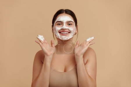 Téléchargez les photos : Cleaning Face. Smiling Full Figured Woman Cleaning Facial Skin with Foam Soap. Happy Girl Cleansing Face Applying Facial Cleanser Closeup. High Resolution - en image libre de droit