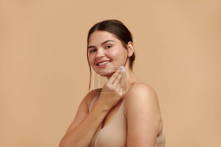 Photo for Woman Cleaning Face With White Pad. Beautiful Girl Removing Makeup White Cosmetic Cotton Pad. Happy Female Taking Off Makeup From Facial Skin With Cosmetic Pad. Hight Quality Image - Royalty Free Image