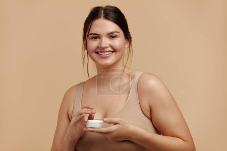 Foto de Beauty Woman Holding Face Cream. Closeup Of Female Model With Fresh Skin Posing with Cream Bottle In Hands. Skincare Concept. High Resolution - Imagen libre de derechos