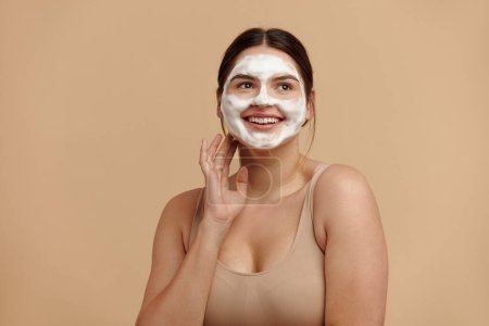 Foto de Cleaning Face. Caucasian Plus Size Woman Cleaning Facial Skin with Foam Soap. Happy Girl Cleansing Face Applying Facial Cleanser Closeup. High Resolution - Imagen libre de derechos