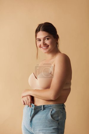 Foto de Plus Size Woman in Jeans. Overweight Smiling Woman Demonstrating Weight Loss. Happy Girl Showing Large Jeans And Looking At Camera - Imagen libre de derechos