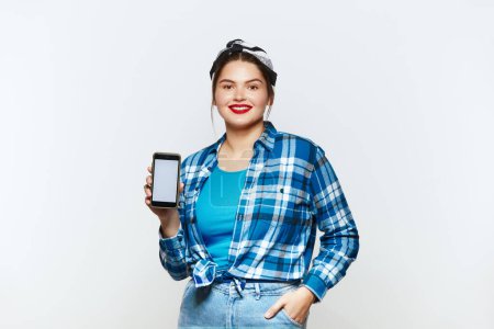 Photo for Smiling Woman Showing Blank Smartphone. Plus Lady Showing White Blank Screen Cellphone, Enjoying Mobile Quality. Empty Copy Space for Advertisement, Indoor Studio Shot - Royalty Free Image