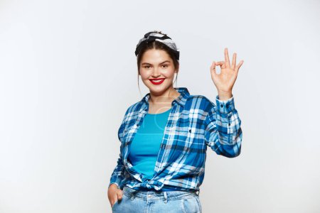 Téléchargez les photos : Smiling Woman Ok Gesture Isolated. Portrait of Satisfied Plus Size Girl Standing, Looking at Camera and Showing Ok Sign Gesture. Indoor Studio Shot Isolated on White Background - en image libre de droit
