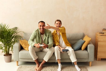 Téléchargez les photos : Happy Couple Playing Video Games. Boyfriend And Girlfriend Sitting On Couch In Living Room Enjoying Playing Video Games And Spending Time Together. Enjoying Moment On Weekend Concept - en image libre de droit