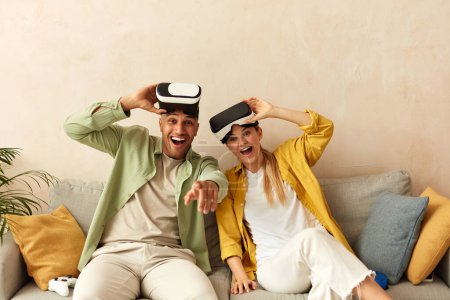 Foto de Happy Couple Trying VR. Boyfriend And Girlfriend Enjoying Virtual Reality In Their Apartment. Cheerful People Having Fun With New Trends Technology. Gaming concept - Imagen libre de derechos