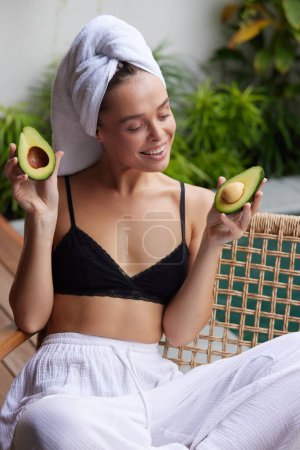 Foto de Smiling Woman Holding Avocado. Beautiful Happy Woman With Smooth Soft Clean Skin, Natural Makeup Holding Organic Green Avocado In Hand. Skin Care And Beauty. Healthy Lifestyle And Nutrition Concept - Imagen libre de derechos