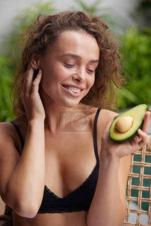 Téléchargez les photos : Smiling Woman Holding Avocado. Beautiful Happy Woman With Smooth Soft Clean Skin, Natural Makeup Holding Organic Green Avocado In Hand. Skin Care And Beauty. Healthy Lifestyle And Nutrition Concept - en image libre de droit