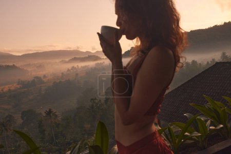 Téléchargez les photos : Femme bénéficie d'une retraite de yoga relaxante dans un magnifique complexe balinais avec une vue imprenable sur le lever du soleil et le volcan Agung. Concept voyage et bien-être. - en image libre de droit