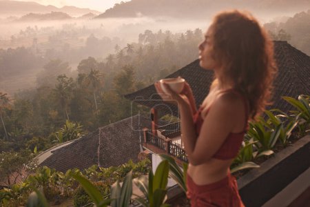 Téléchargez les photos : Femme bénéficie d'une retraite de yoga relaxante dans un magnifique complexe balinais avec une vue imprenable sur le lever du soleil et le volcan Agung. Concept voyage et bien-être. - en image libre de droit