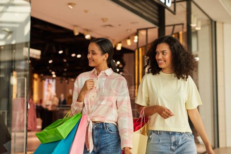 Foto de Dos mujeres comprando, llevando bolsas de compras, sonriendo, feliz, centro comercial, moda, amigos. - Imagen libre de derechos