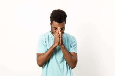 Photo for A man in casual attire shows signs of stress and exhaustion, holding his face in his hands against a white background. - Royalty Free Image
