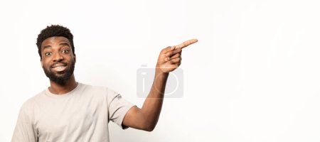 Foto de Alegre hombre afroamericano casualmente vestido señalando a la derecha, espacio de copia para la publicidad. - Imagen libre de derechos