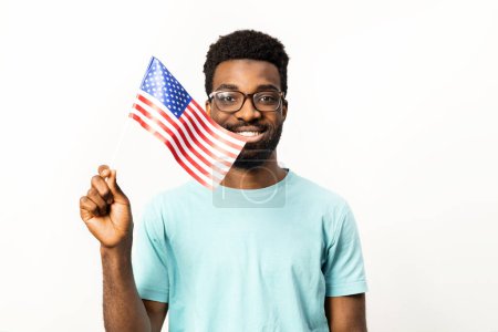 Foto de Retrato del hombre afroamericano sosteniendo orgullosamente la bandera estadounidense, representando el patriotismo aislado sobre un fondo blanco. Simbolizando alegría, orgullo y diversidad. - Imagen libre de derechos