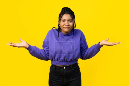 Photo for Woman shrugging shoulders on a vibrant yellow background, expressing uncertainty. - Royalty Free Image