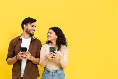 Foto de Pareja feliz con teléfonos inteligentes sobre fondo amarillo, Redes Sociales, Comunicación, Tecnología, Amor, Conectividad, Estilo de vida - Imagen libre de derechos