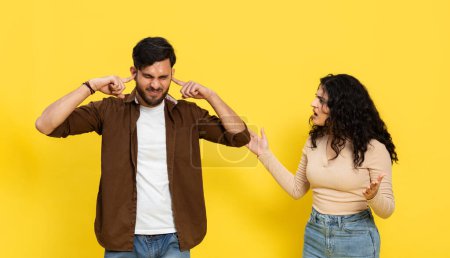 Photo for Frustrated Indian Man Ignoring Woman Pointing Finger, Couple Argument Concept, Yellow Background - Royalty Free Image