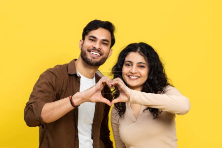 Photo for Couple Making Heart Shape With Hands Against Yellow Background - Royalty Free Image