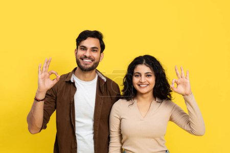 Téléchargez les photos : Couple heureux montrant bien signe sur fond jaune - geste positif, relation, et concept de satisfaction - en image libre de droit