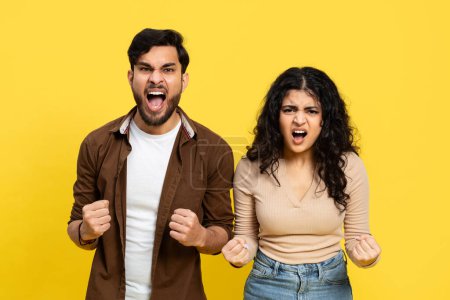 Wütendes Paar schreit mit geballten Fäusten auf gelbem Hintergrund und zeigt Frust und Beziehungsdrama