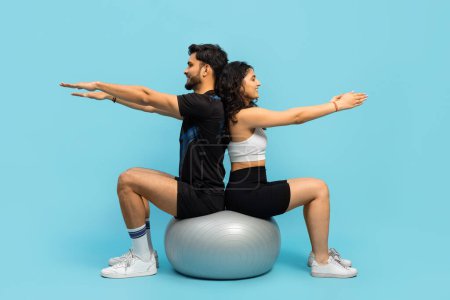 Téléchargez les photos : Couple de conditionnement physique faisant de l'exercice avec ballon de gymnastique sur fond bleu, Style de vie actif, Entraînement de force, Entraînement de force, Sportwear, Partenariat - en image libre de droit