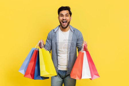 Photo for Excited Man With Colorful Shopping Bags On Yellow Background, Sale, Discount, Happy Consumer, Retail Joy, Smiling Shopper, Seasonal Offer, Young Adult Buying - Royalty Free Image
