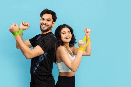 Fitness-Paar lächelt mit Widerstandsbändern auf blauem Hintergrund, Workout, Gesunder Lebensstil, Gemeinsam, Glücklich, Aktiv