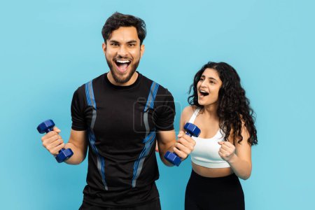 Foto de Pareja de fitness haciendo ejercicio junto con pesas sobre fondo azul, estilo de vida activo, vida saludable - Imagen libre de derechos