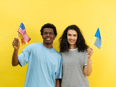 Foto de Feliz pareja multiétnica sosteniendo banderas estadounidenses y de la Unión Europea - Imagen libre de derechos