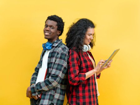 Foto de Jóvenes estudiantes con auriculares y tableta contra fondo amarillo, concepto de estilo de vida de tecnología casual - Imagen libre de derechos