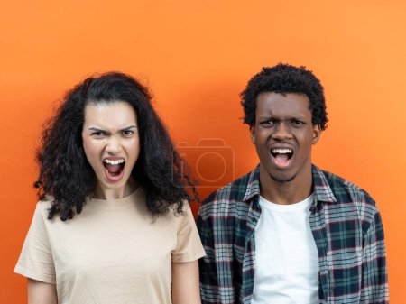 Frustrated Young Couple Arguing With Angry Expressions Against Orange Background - Relationship Problems, Conflict Resolution, Emotional Stress