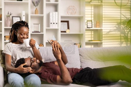 Téléchargez les photos : Couple heureux relaxant à la maison avec café, moment franc de joie et d'affection, salon confortable - en image libre de droit