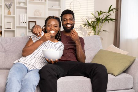 Téléchargez les photos : Couple bénéficiant d'un film à la maison avec des collations - en image libre de droit