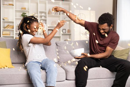 Photo for Joyful Couple Having Fun With Popcorn On Couch. African American Man And Woman Enjoying Playful Time, Home Entertainment. Lifestyle, Leisure, Togetherness Concept Captured. - Royalty Free Image