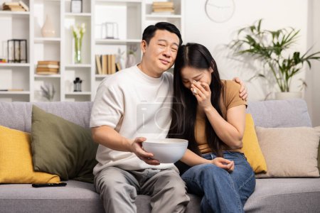 Photo for Asian couple movie night. Sad people enjoying a movie together with a bowl of snacks, evoking warmth and togetherness. - Royalty Free Image