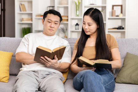 Photo for Couple Reading Books Together On Sofa, Serene Home Leeisure, Quality Time, Educational Activity, Relaxed Atmosphere, Adult Education, Casual Enjoyment, Asian Couple Leisure Time, Reading Session. - Royalty Free Image