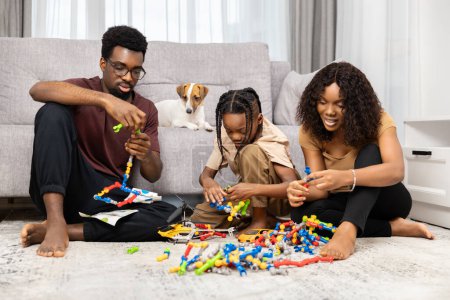 Photo for Happy Family Playing With Toys Together At Home With Dog Watching, Joyful Indoor Activity - Royalty Free Image