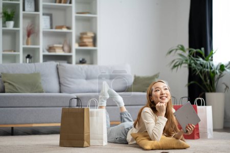 Foto de Mujer joven feliz con bolsas de compras Relajante en casa, Disfrutando del éxito de compras en línea, Estilo de vida casual en apartamento moderno - Imagen libre de derechos