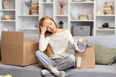 Photo for Young Woman Feeling Overwhelmed While Unpacking Boxes In Living Room, Expressing Exhaustion, Stress And Moving House Fatigue. Concept Of New Home And Personal Challenges. - Royalty Free Image