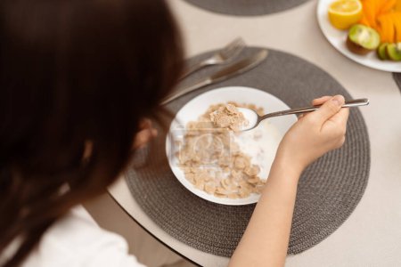 Photo for Healthy Breakfast: Woman Enjoying Cereal With Fruit, Focus on Hand Holding Spoon, Fresh Start, Morning Routine, Nutritious Meal, Wellness. - Royalty Free Image